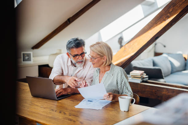 thoughtful older couple sitting reviewing kitchen table paperwork