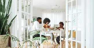 A group of three people sitting in a house and discussing at a table.