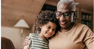 A grandmother embracing her grandson in a cottage.