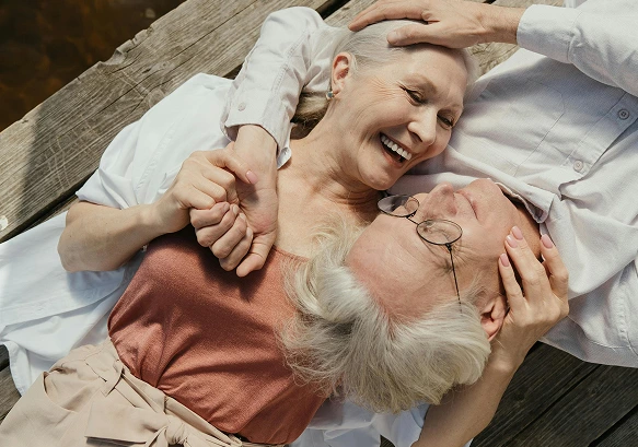 A retired elderly couple embracing and smiling at each other